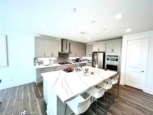 kitchen with appliances with stainless steel finishes, gray cabinets, wall chimney range hood, and tasteful backsplash