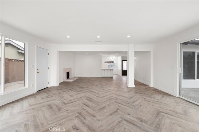 unfurnished living room with baseboards, a fireplace with raised hearth, and recessed lighting