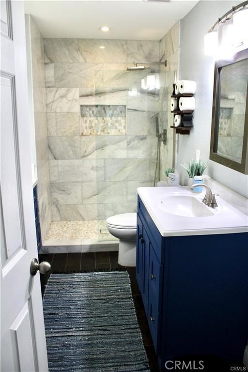 bathroom featuring tiled shower, vanity, and toilet