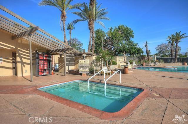 pool featuring a community hot tub, a patio area, fence, and a pergola