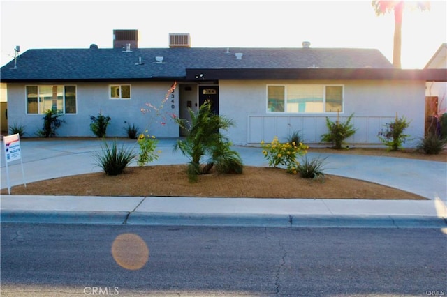 ranch-style house with driveway, central AC, and stucco siding