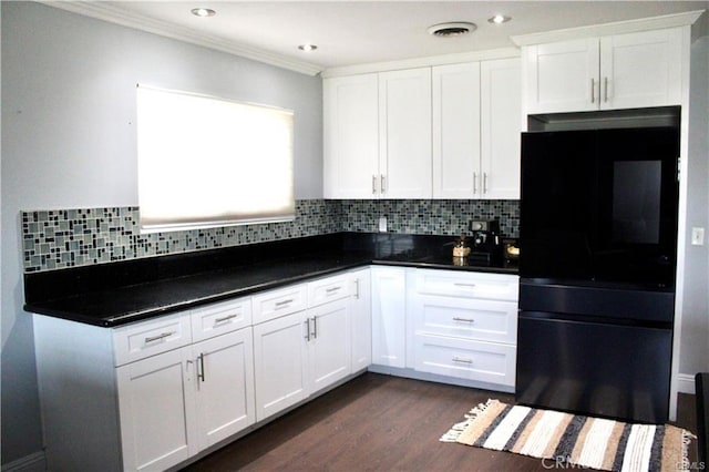 kitchen featuring dark wood-style floors, visible vents, backsplash, freestanding refrigerator, and white cabinetry