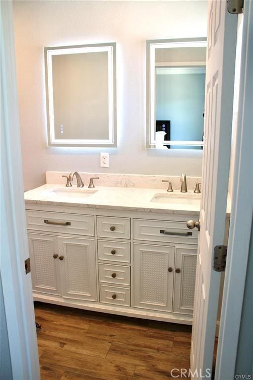 bathroom featuring double vanity, wood finished floors, and a sink