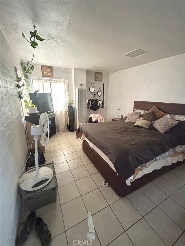 bedroom featuring a textured ceiling, light tile patterned flooring, and attic access