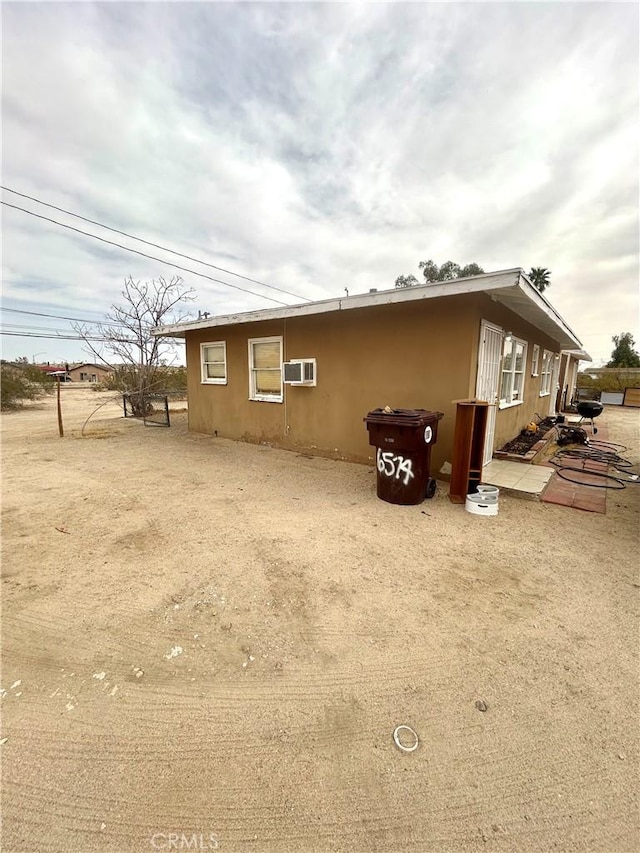 view of property exterior featuring a patio area, a wall mounted AC, and stucco siding