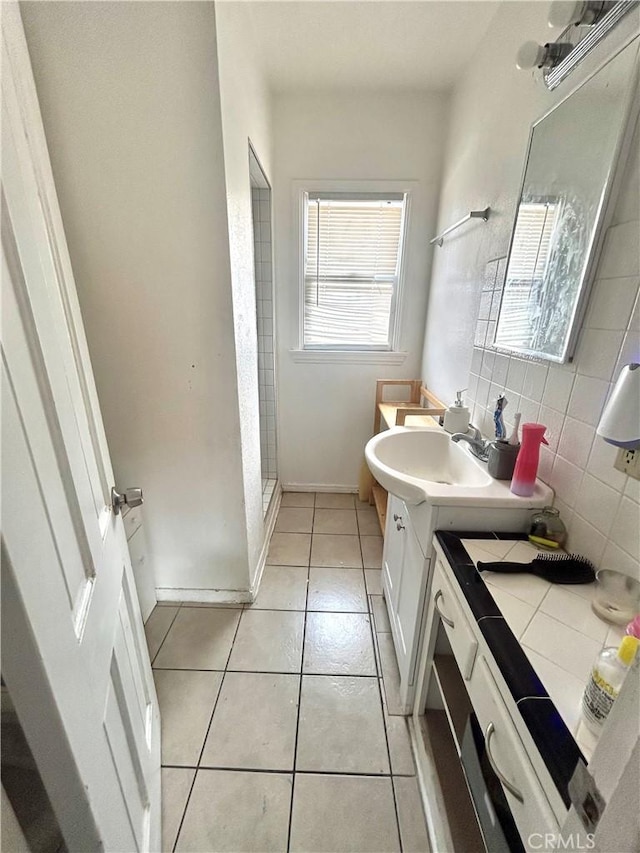 bathroom with backsplash, a shower stall, vanity, tile patterned flooring, and baseboards