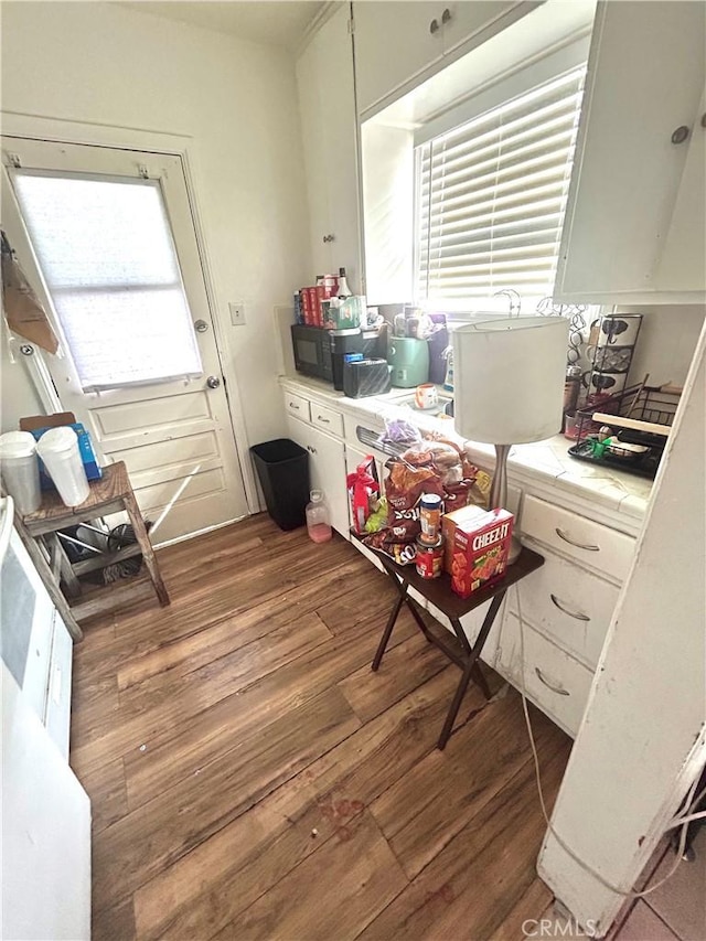 interior space with black microwave, wood finished floors, and tile counters