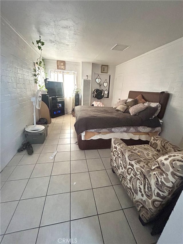 tiled bedroom featuring brick wall and a textured ceiling