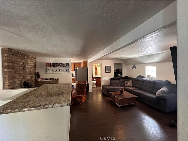 living room featuring a textured ceiling, dark wood-style flooring, and a brick fireplace