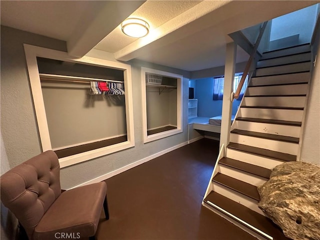 finished below grade area with a textured wall, stairway, and baseboards