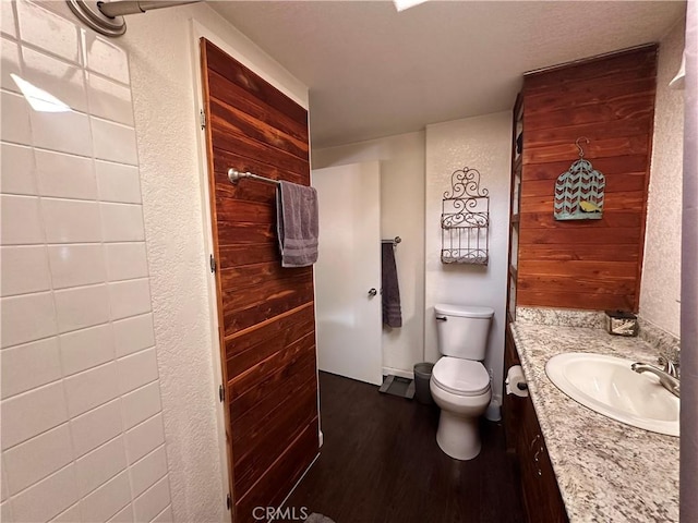 bathroom featuring a textured wall, vanity, wood finished floors, and toilet