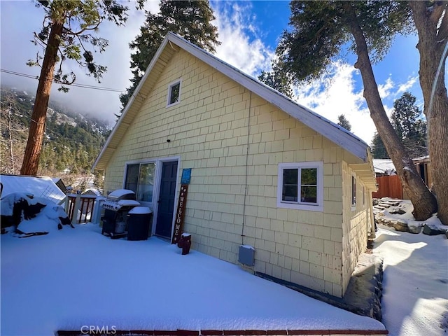 view of snow covered exterior with fence and a patio