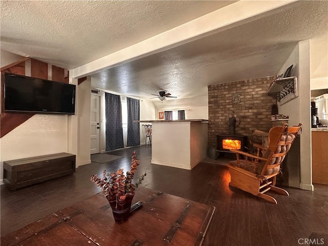 living room with a wood stove, ceiling fan, a textured ceiling, and hardwood / wood-style flooring