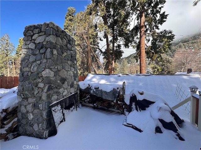 yard covered in snow featuring a fireplace and fence