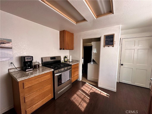 kitchen featuring a textured wall, dark wood-type flooring, stainless steel gas range, and brown cabinets