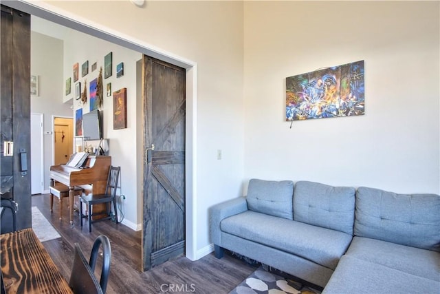 living area featuring dark wood-type flooring, baseboards, and a towering ceiling