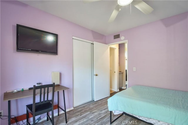 bedroom with visible vents, baseboards, wood finished floors, a closet, and a ceiling fan