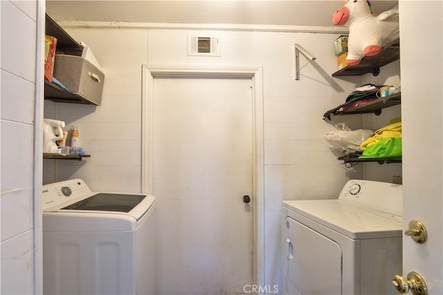 laundry room featuring washer and dryer, laundry area, concrete block wall, and visible vents