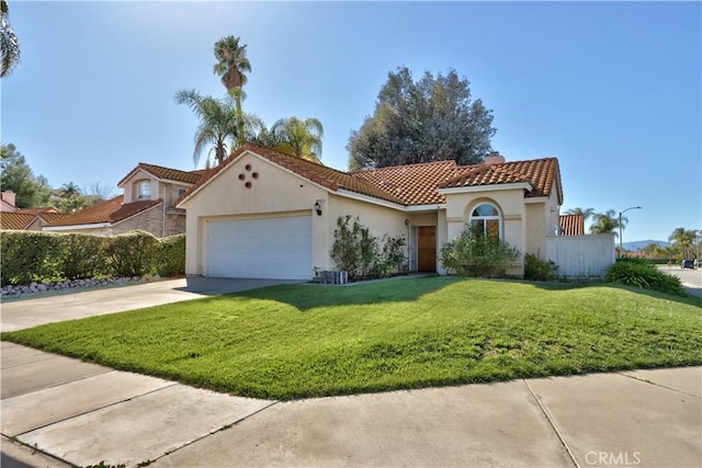 mediterranean / spanish-style home with stucco siding, concrete driveway, a front lawn, and a tile roof