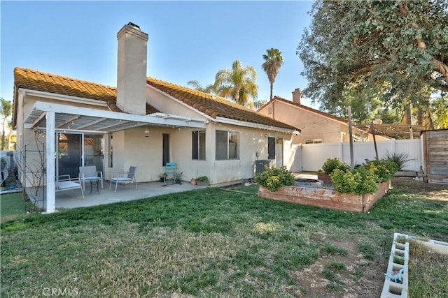 back of house featuring fence, a yard, a chimney, stucco siding, and a patio area