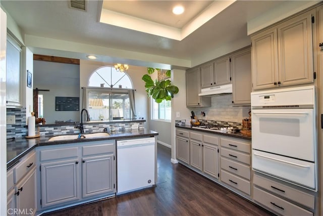 kitchen featuring visible vents, under cabinet range hood, white appliances, a warming drawer, and a sink