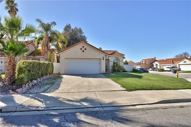 mediterranean / spanish-style home with concrete driveway, a tile roof, a front yard, stucco siding, and a garage