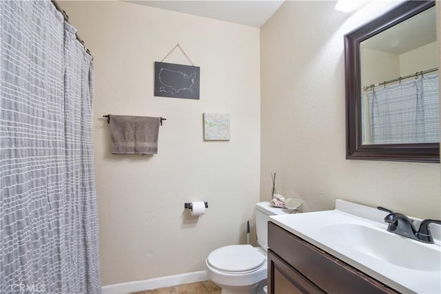 full bathroom with toilet, vanity, and baseboards