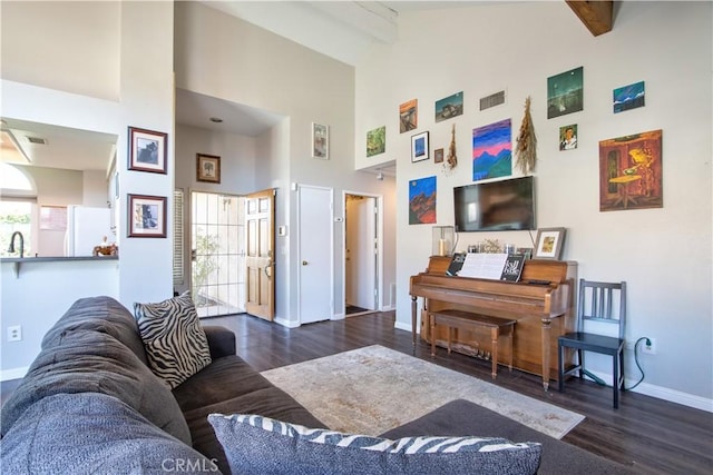 living area with beamed ceiling, plenty of natural light, baseboards, and wood finished floors