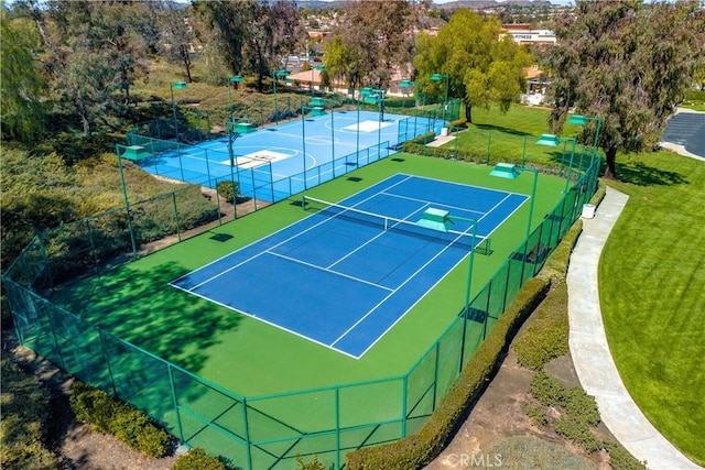 view of sport court with a lawn and fence