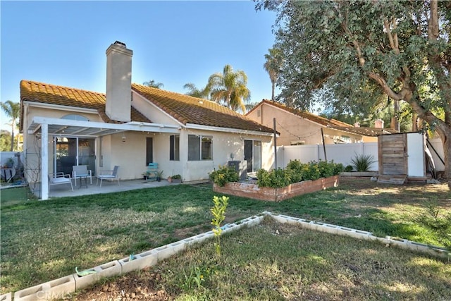 back of house featuring fence, a tile roof, stucco siding, a yard, and a patio area