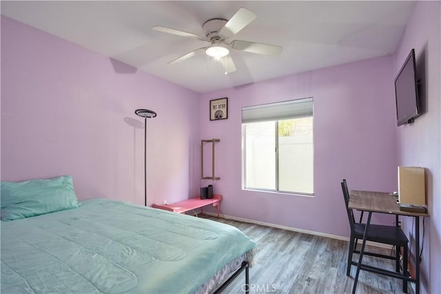 bedroom with a ceiling fan, wood finished floors, and baseboards