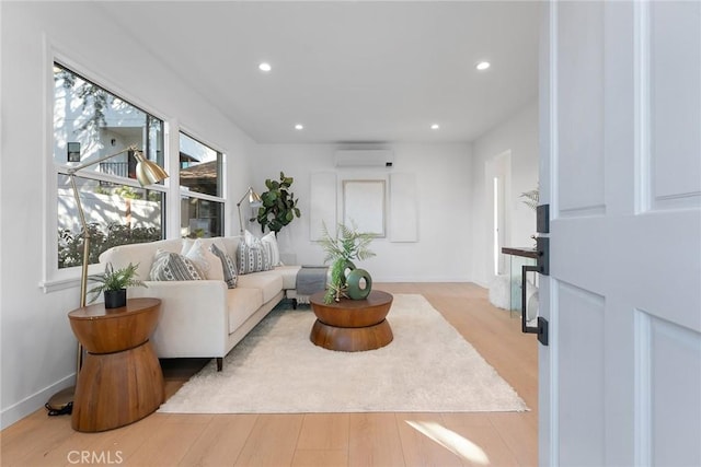 living area featuring baseboards, light wood finished floors, a wall mounted AC, and recessed lighting