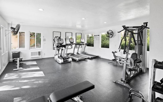 exercise room featuring recessed lighting, an AC wall unit, plenty of natural light, and baseboards