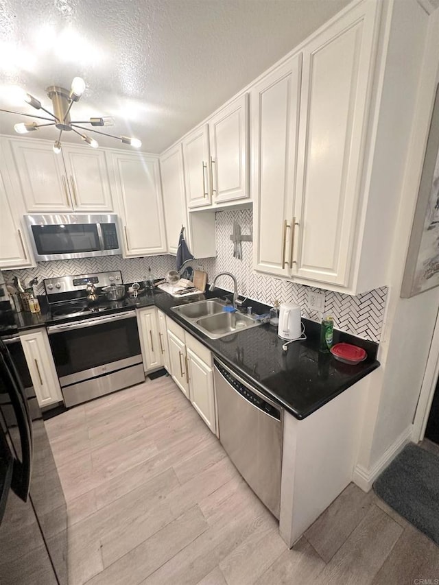 kitchen featuring appliances with stainless steel finishes, dark countertops, a sink, and backsplash