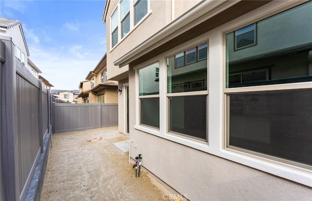 view of side of home with a fenced backyard and stucco siding