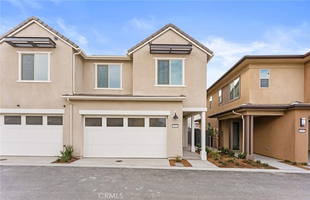 townhome / multi-family property with a garage, a tile roof, and stucco siding