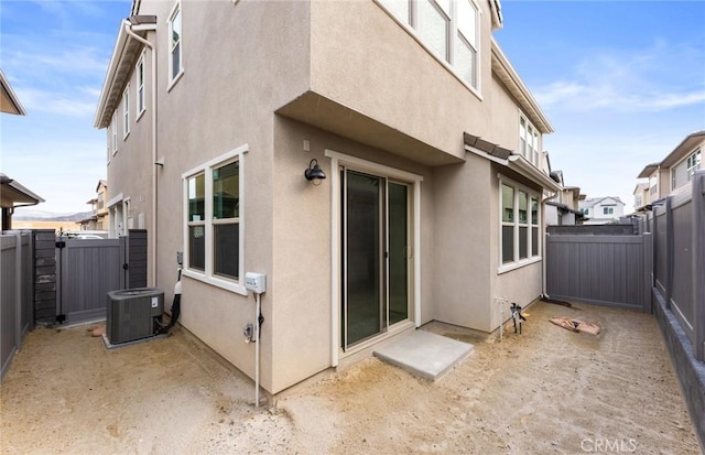 back of property with a fenced backyard, central AC, and stucco siding