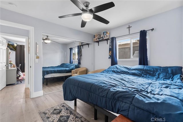 bedroom featuring a closet, multiple windows, ceiling fan, and light wood finished floors