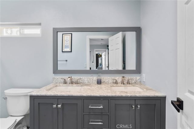 full bath featuring double vanity, toilet, and a sink