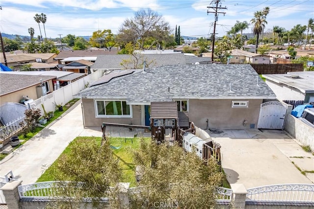 rear view of house with stucco siding, fence private yard, and a gate