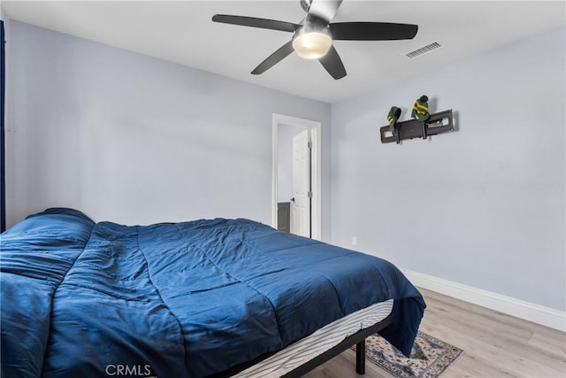 bedroom with ceiling fan, wood finished floors, visible vents, and baseboards