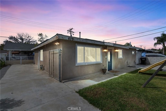 view of front of home featuring stucco siding, a playground, a front lawn, and fence