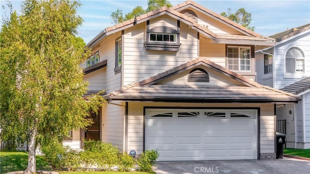 view of front of property with driveway, a tiled roof, and an attached garage