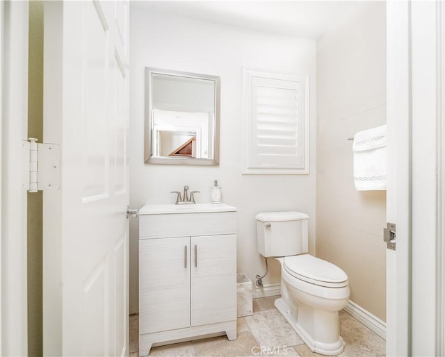 half bathroom with toilet, tile patterned flooring, baseboards, and vanity