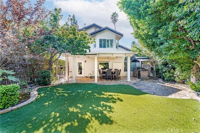 rear view of property featuring a patio, a yard, fence, and stucco siding