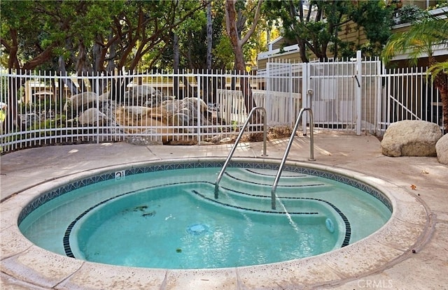 view of pool with a community hot tub and fence