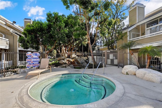 view of swimming pool featuring a community hot tub and fence