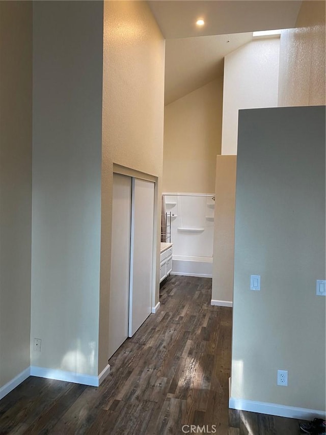 hallway featuring dark wood-style floors, high vaulted ceiling, elevator, and baseboards