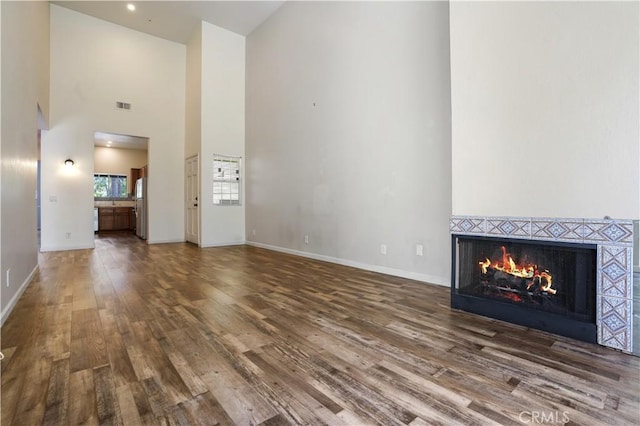 3690 S Bear St Unit 5, Santa Ana, CA 92704 - unfurnished living room featuring high vaulted ceiling, a tiled fireplace, baseboards, wood finished floors, and visible vents
