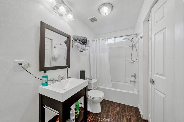 full bath with toilet, shower / tub combo, wood finished floors, visible vents, and vanity